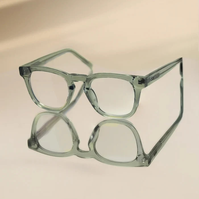 Sea Salt Grey || Square modern prescription eyeglasses with transparent sea salt grey frame resting on reflective surface