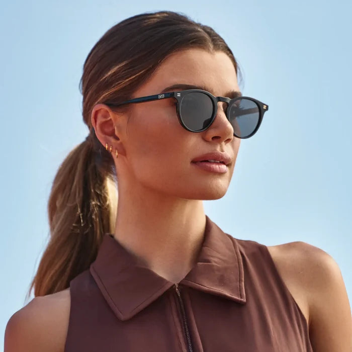 Black / Black Lens || Woman wearing Round Sports Performance Sunglasses with Black Acetate Frame and Black Polarized Oleophobic Lens outdoors