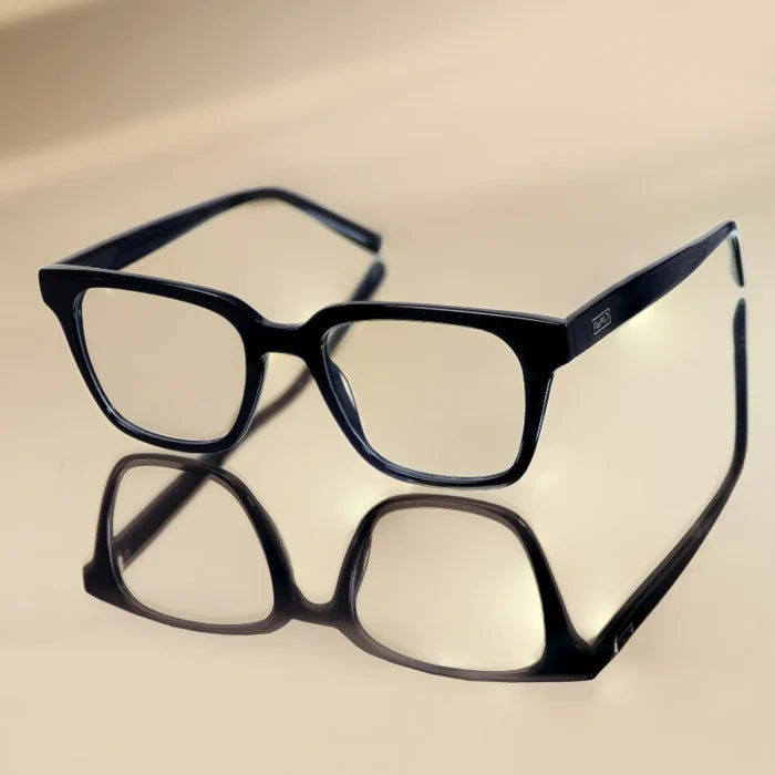 Glossy Black || Modern rectangular prescription glasses with black frame and integrated bridge resting on reflective surface