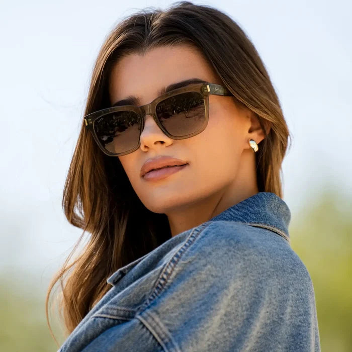 Crystal Moss Green / Amber || Square modern prescription sunglasses with thick translucent acetate green frame and flat lenses worn by a woman outdoors