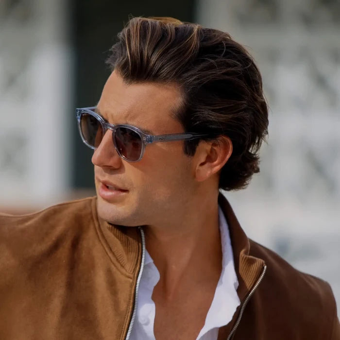 Denim Blue / Amber || Model wearing Men's Retro-Inspired Round Prescription Sunglasses with Blue Acetate Frame and Brown Prescription Lenses