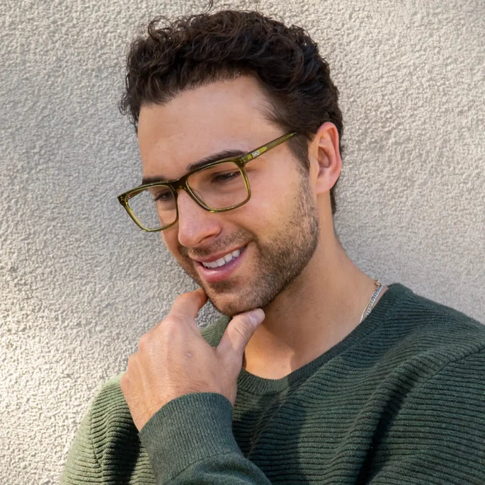 Crystal Sage Green || Blue Light glasses with angular olive green frames worn by smiling man against textured wall