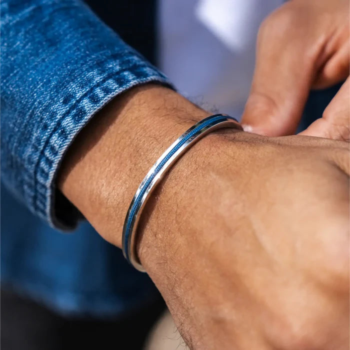 Silver / Denim Blue || Close up of a model wearing the adjustable Water Resistant Men's Cuff Bracelet with Silver and Blue Details in natural lighting.
