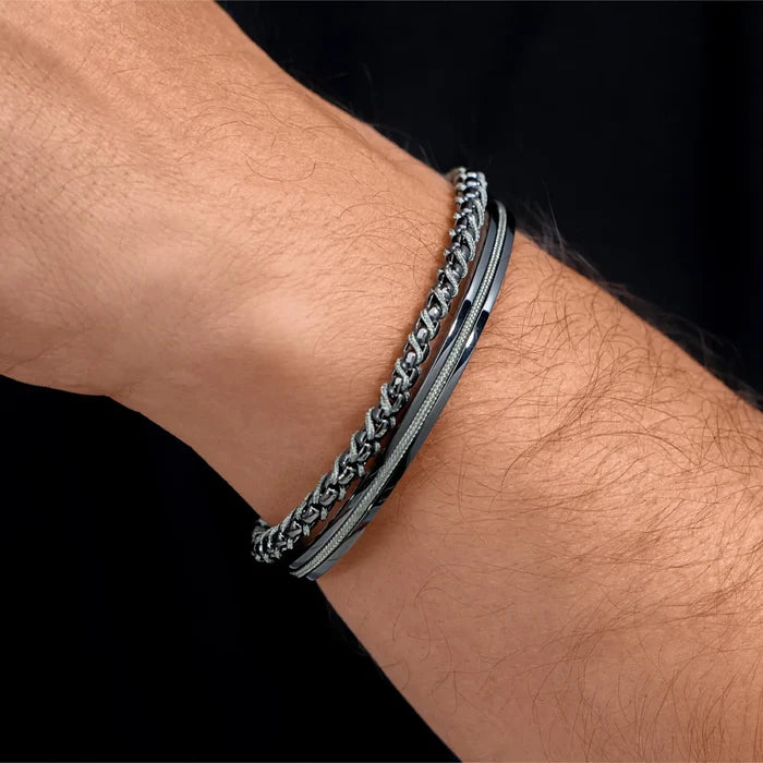 Gunmetal / Olive Green || Man’s wrist adorned with dual silver and olive toned chain and textured bracelets on black background
