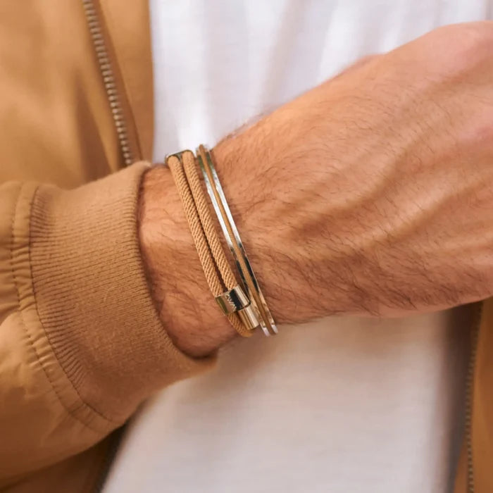 Desert Tan / Silver || Tan cord bracelet paired with sleek polished silver bangle on wrist over casual jacket sleeve