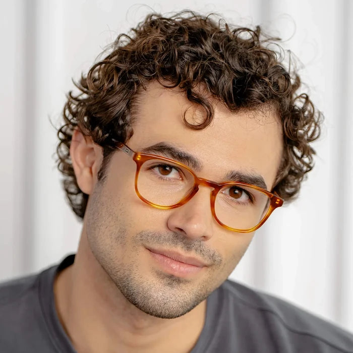 Honey Tortoise || Miles blue light glasses with honey tortoise translucent frames worn by man with curly hair in natural lighting