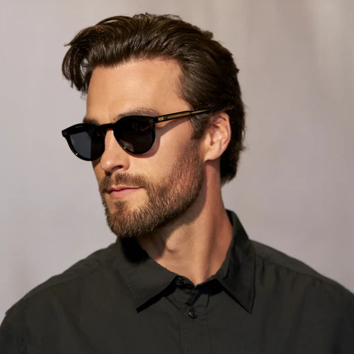 Black / Triple Black Lens || Side view of man wearing Round Polarized Sunglasses with Black Frame and Black Lens against a grey background