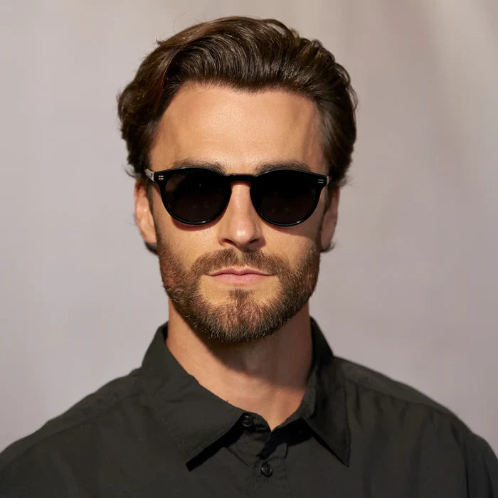 Black / Triple Black Lens || Front view of man wearing Round Polarized Sunglasses with Black Frame and Black Lens against a grey background