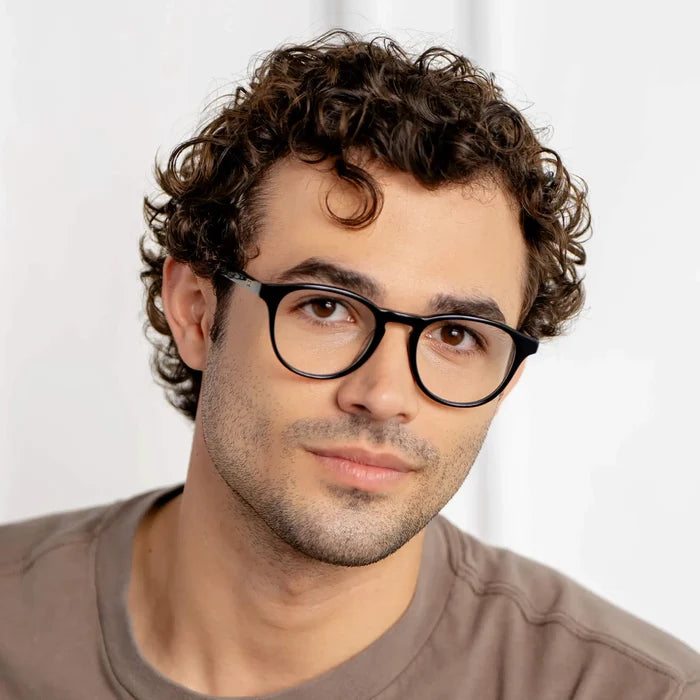 Black || Wade round blue light glasses with black frames worn by man with curly hair against neutral background