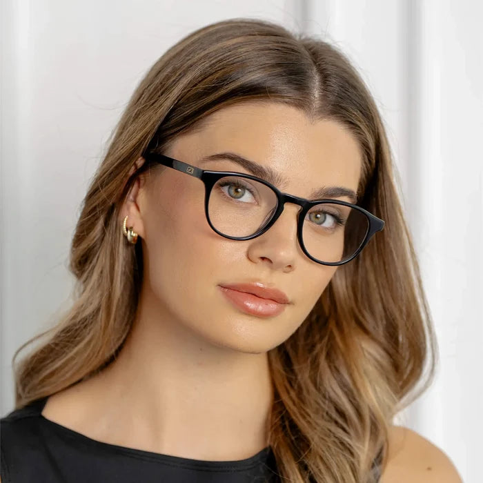 Black || Close up of Round prescription eyeglasses with lightweight black acetate frame and keyhole bridge worn by woman in natural light