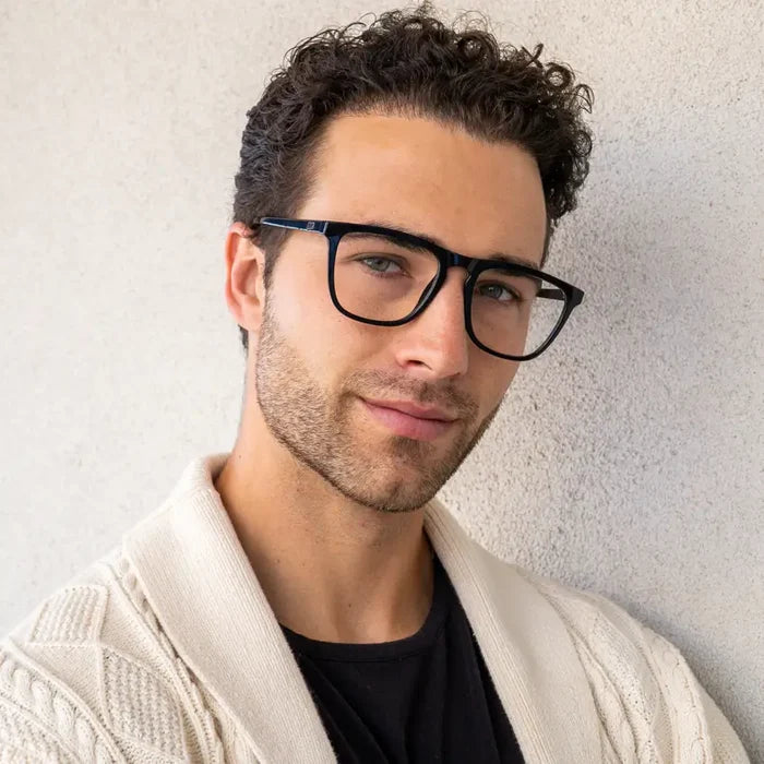 Man wearing sleek square black frames with strong browline and notched nose bridge in neutral setting
